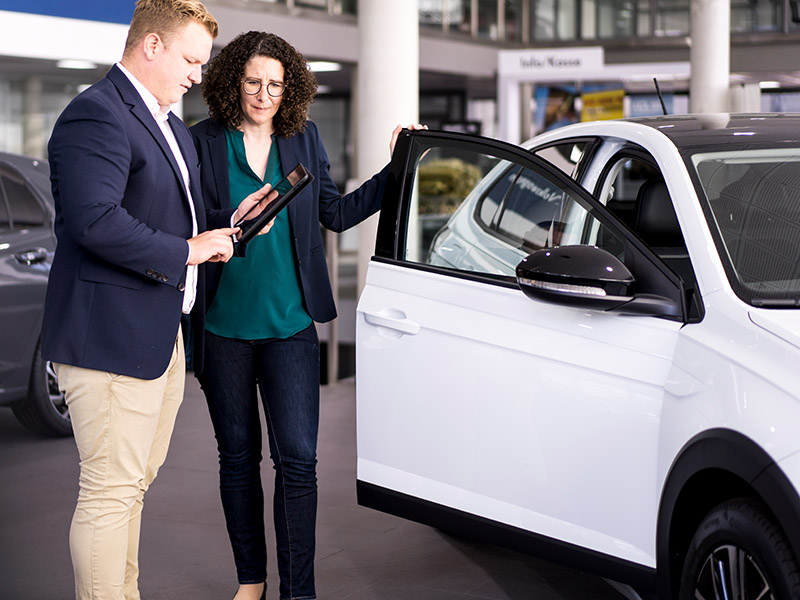 Eine Frau lässt sich im Autohaus ein Fahrzeug erklären.